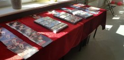 Zdjęcie w kolorze przedstawiające stół z broszurami, ulotkami i walizką narkotykową.