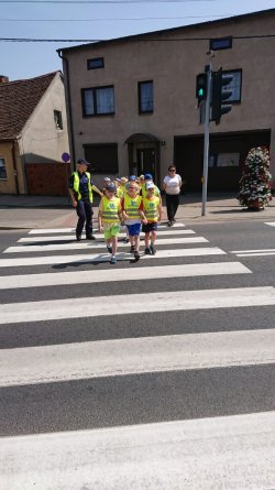 Zdjęcie w kolorze - dzielnicowa uczy przechodzenia dzieci przez przejście dla pieszych