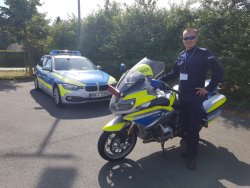 zdjęcie w kolorze - policjant przy motorze niemieckiej Policji